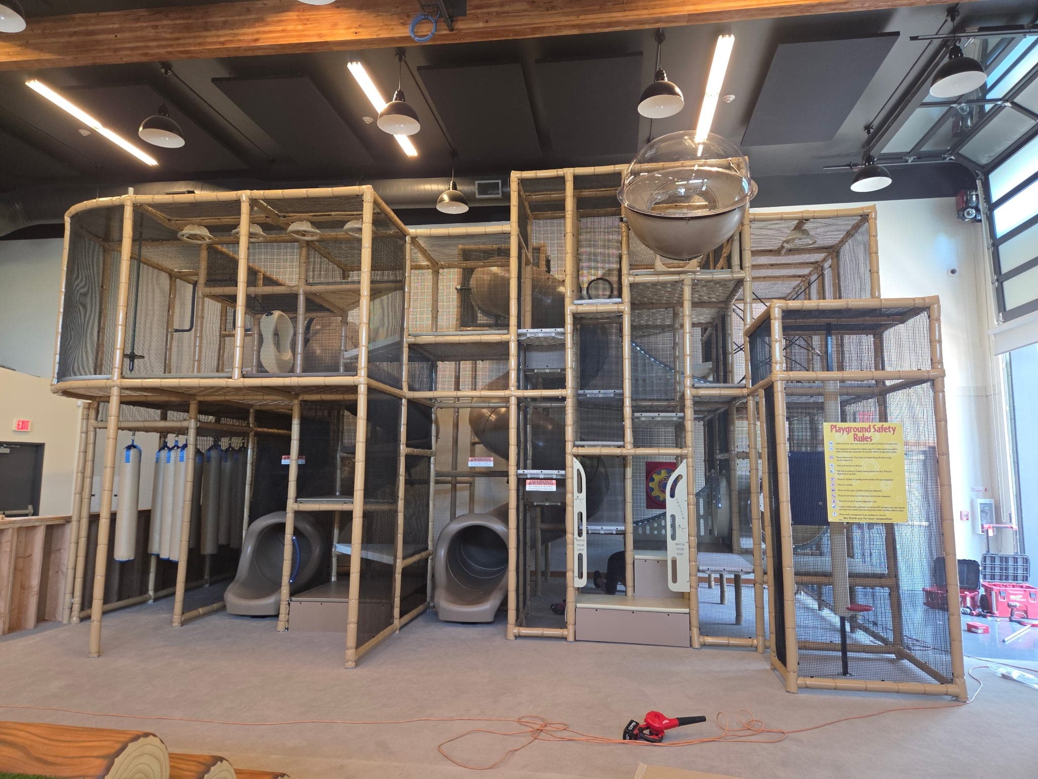 A new indoor playland we built: a two-level tan frame wrapped in netting, with tube slides and a clear bubble window
