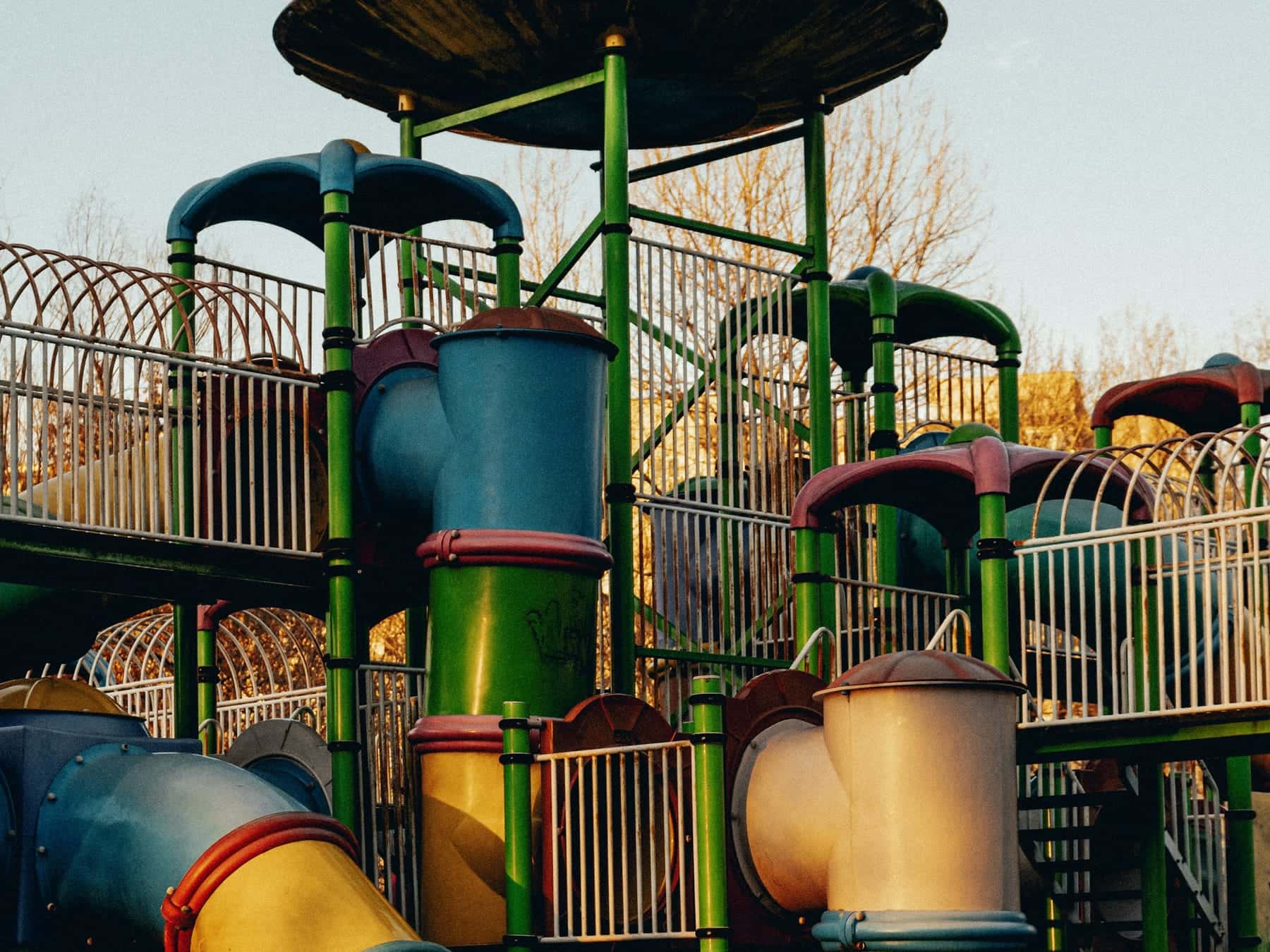 A tall play structure with a run of jointed tube slides and railings